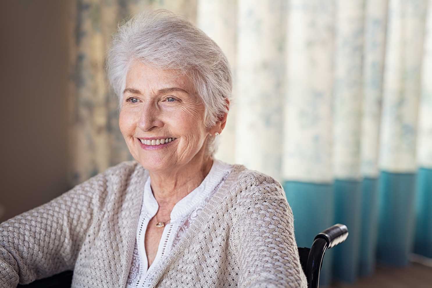 Happy old woman sitting on wheelchair in a nursing home