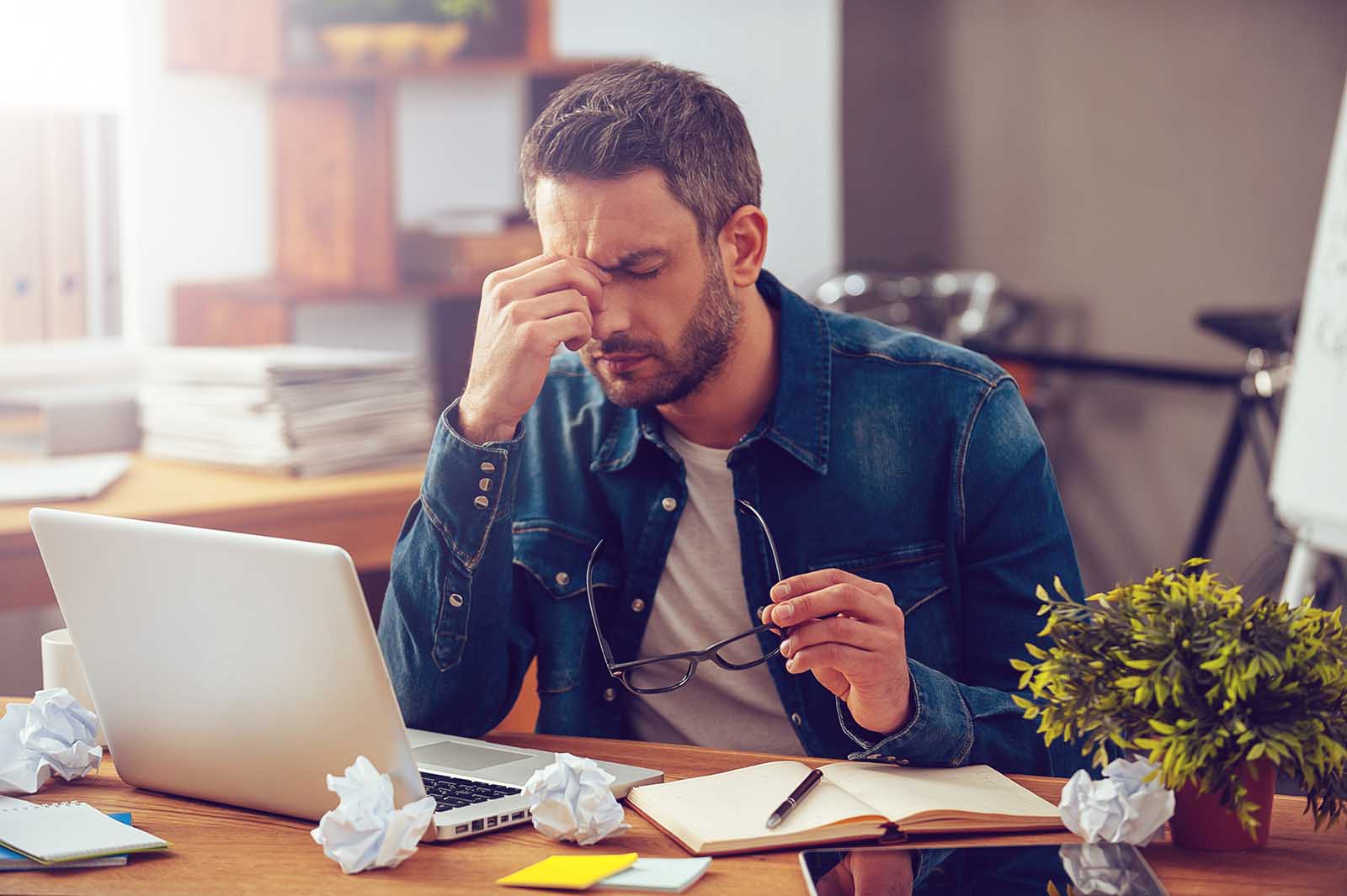Frustrated young man massaging his nose and keeping eyes closed